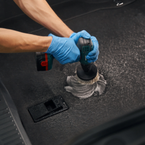 Cropped view of service worker at Jax Auto Spa in Jacksonville wearing protective gloves using mechanic brush with foam for cleaning car luggage carrier