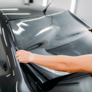 Male specialist at Jax Auto Spa with car tinting film in hands Installation process tinted auto glass installing procedure in Jacksonville Florida